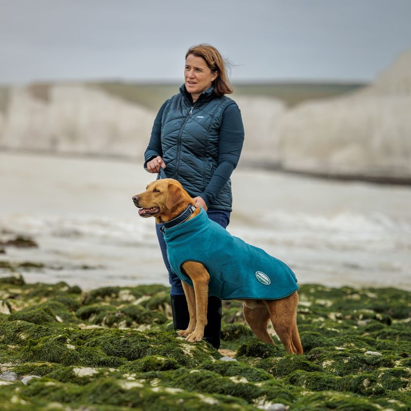 female model stood on beach in winter with Labrador wearing weatherbeeta green tec fleece zip dog coat
