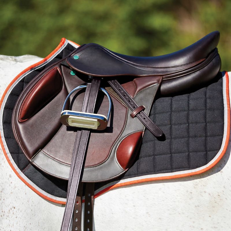 brown saddlle sat ontop of weatherbeeta therapy-tec jump saddle pad in bl with red and white piping
